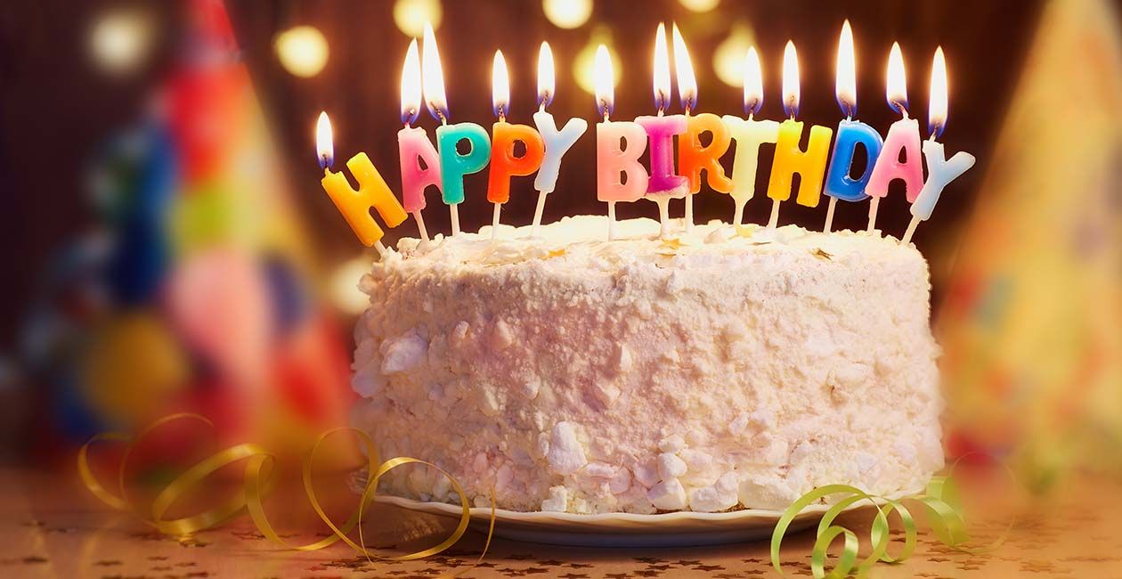 A birthday cake with lit candles that say happy birthday
